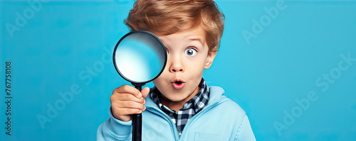Small boy with magnifying glass on blue background.