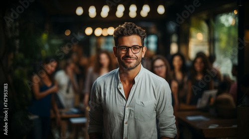 20s latino male office worker, smiling and standing in front of his co-workers, wearing glasses and white shirt. 