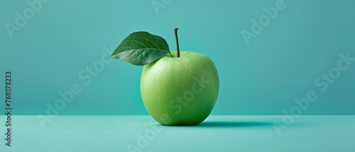 A green apple with a leaf attached to its side is positioned against a blue backdrop on a green background