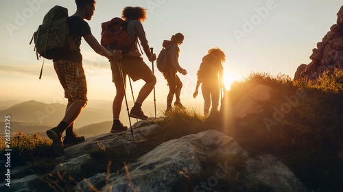 Group of mixed age hikers are standing on mountain slope and looking at sunset