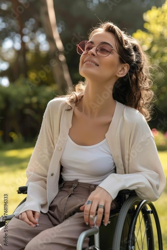 paraplegic female wheelchair user sitting in narrow lightweight wheelchair wearing glasses, enjoying the park 