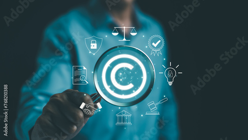 Digital copyright or patent concept. Author rights and patented intellectual property. Businessman holding a magnifying glass focuses on a copyright symbol surrounded by legal icons. trademark license