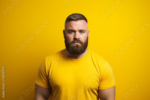 Portrait of a bearded man in a yellow T-shirt on a yellow background