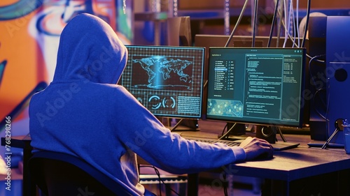 Hooded spy in underground hideout trying to steal valuable data by targeting governmental websites with weak security. Espionage specialist doing cyber attacks to gain access to sensitive info