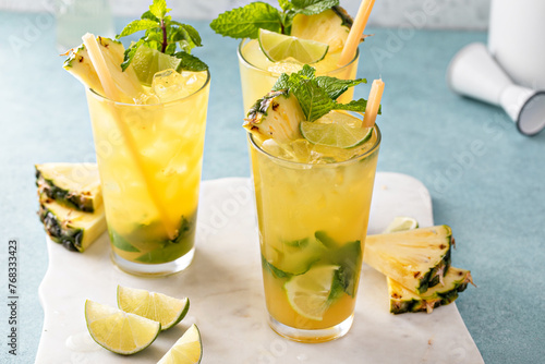 Pineapple mojito with mint and lime wedges garnished with mint leaves and pineapple slices