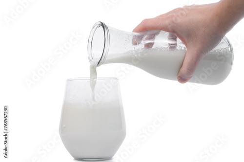 Świeże mleko nalewane ze szklanego dzbanka do szklanki na białym tle