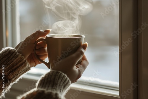 closeup of hands holding a warm mug, steaming near window