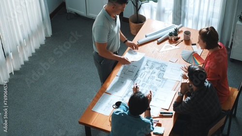 Top view of interior designer planing building while project manager working and holding coffee. Group of engineer brainstorming idea and designing house structure while presenting idea. Symposium.