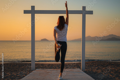 Joga, młoda dziewczyna praktykuje asany na wakacjach nad morzem. Wschód słońca na greckiej wyspie Kos. Ćwiczenia rozciągające, sport na powietrzu. 