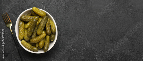 Bowl of tasty pickled cucumbers on dark background with space for text, top view