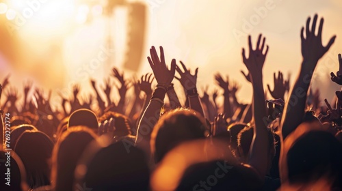 A lively crowd of people with their hands raised in excitement at a concert event.