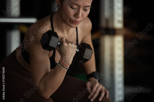 Close up, fitness girl lifting dumbbell weights at the gym, doing exercises with dumbbell, fitness muscular body