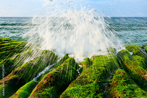 Tidal waves splash up radial water sprays when crashing on the shore of massive green rocky trenches at Laomei of New Taipei City, a scenic spot in spring voted as one of Taiwan's eight secrets by CNN