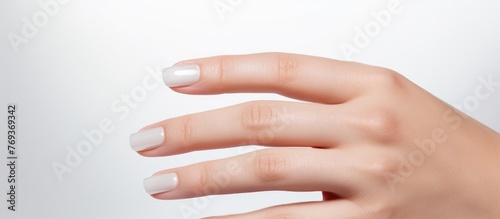 A closeup shot showcasing a womans hand with white nails against a white backdrop, highlighting the details of her nails and wrist as a fashion accessory in magenta nail polish