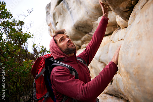 Man, hiking and climbing mountain with backpack on for fitness, health and adventure. Person, outdoors or in nature looks up at terrain for workout, training and healthy activity or exercise