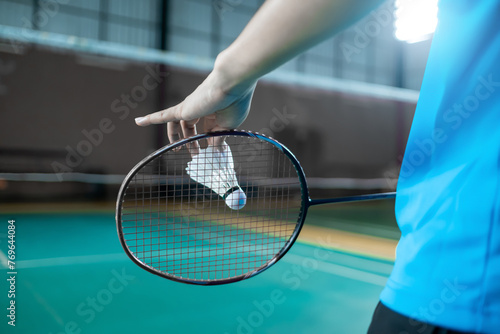 Close up back view badminton serving backhand position with racket and shuttlecock, competitive racket sport activity and leisure concept copyspace.