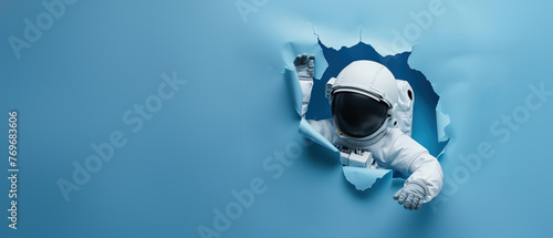 A falling astronaut features prominently through a ripped blue paper scenery, emphasizing motion and surprise