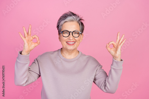 Photo of positive glad retired woman wear trendy jumper two hands demonstrate okey sign nice feedback isolated on pink color background