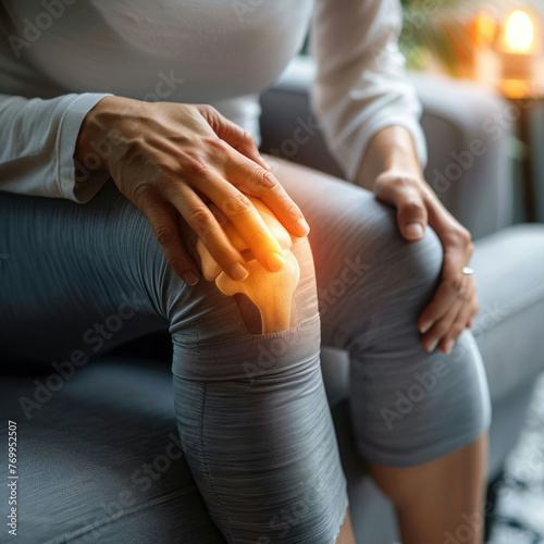Arthritis symptoms. Woman suffering from pain in her knee on sofa indoors, closeup
