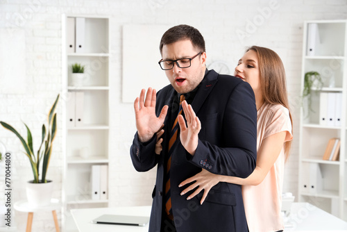 Business woman seducing her male colleague in office. Harassment concept