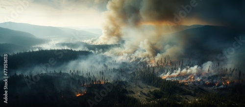 An aerial view of a forest fire in the mountains showing smoke billowing into the sky, polluting the atmosphere and obscuring the horizon