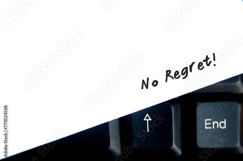 Handwritten text on paper on keyboard : No regret - to live a life without feeling bad about what you did in the past, to a decision without feeling sorrow or remorse for 