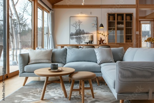 The living room boasts a sofa with wooden legs and armrests crafted from solid wood, featuring blue fabric seats placed atop a light gray carpet on the floor