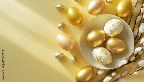 festive easter background with painted golden decoration on easter eggs on pastel yellow table top view and fashion flat lay style