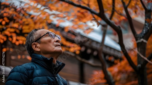 Thoughtful man looking up in courtyard with autumn