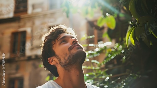 Thoughtful man looking up in sunny courtyard