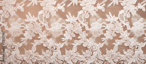 Detailed close-up of white lace fabric featuring intricate floral and leaf designs in a studio setting