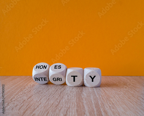 Turned wooden cubes and changes the word integrity to honesty. Beautiful orange background, wooden table. Copy space. Business and honesty and integrity concept.