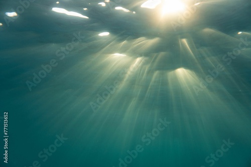 Scenic underwater view of sunlight beaming through water surface