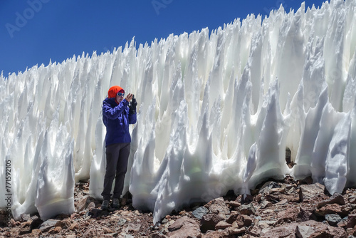  A woman in the Atacama Desert, Chile, captures the towering penitentes with her camera. The ice formations, taller than herself, create a unique and surreal landscape. 