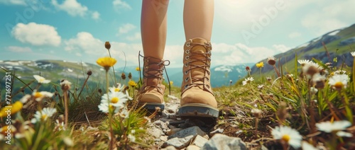 Close up of a female hiker's feet in boots walking on a mountain path with wildflowers, sunshine, and a beautiful landscape. A summer hiking concept in the style of nature photography.