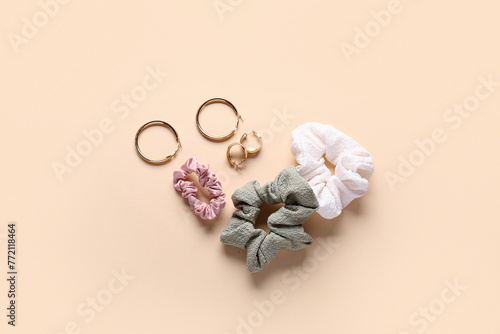 Silk scrunchies with earrings on beige background