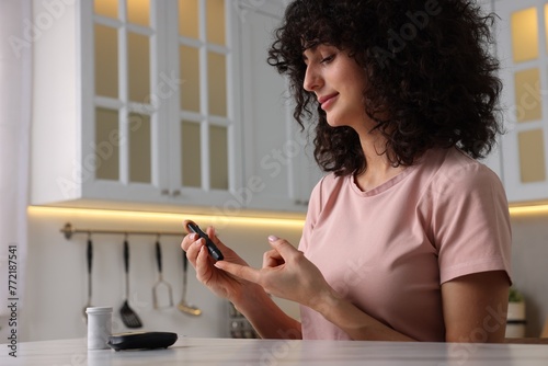 Diabetes. Woman using lancet pen at table in kitchen