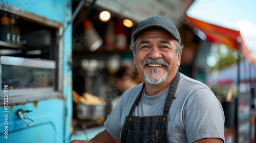 Portrait of happy plump middle aged Mexican chef man smiling near his food truck