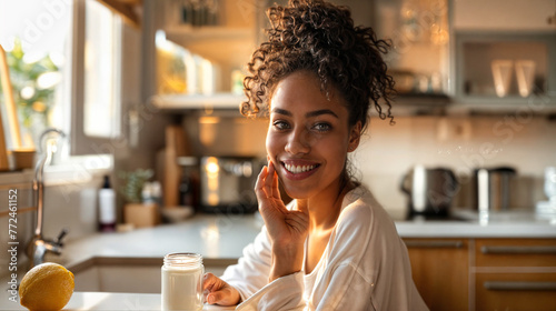 Smiling black-skinned woman sitting in the kitchen of her home, dusk light, looking at camera