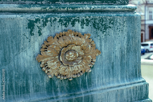 Detail of a decorative element on the side of an ancient ornamental fountain. Fountain in the square of the historic town 