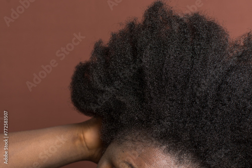 Black afro curly hair with shrinkage, Type 4c hair that is dry with a brown background