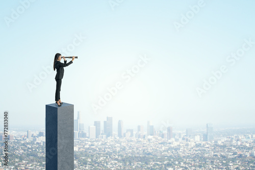 Side view of young businesswoman on concrete bar looking into the distance with telescope. Bright blue sky and city background. Strategy, forecast and goal concept. Mock up place for advertisement.