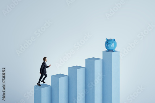 Side view of young businessman climbing blocks to piggy bank on blue background. Financial growth, investment and savings concept. Mock up place.