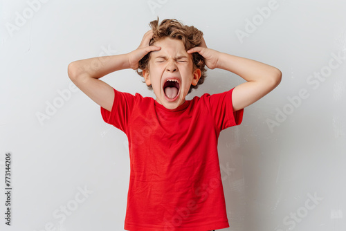 Angry boy in red tee holding his head shouting angrily 