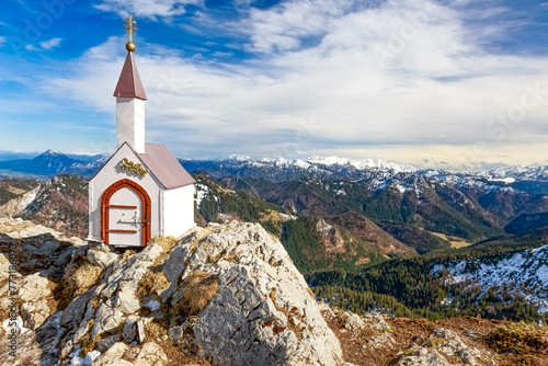 Weiß getünchte Miniatur Kapelle auf dem Hochgern Gipfel in den Chiemgauer Alpen unter teilweise bewölktem Himmel in Bayern Deutschland