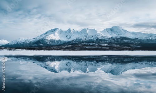 A distant view of snow-capped mountains reflected in the frozen surface of a lake