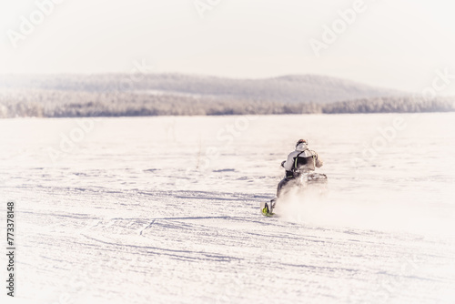 Personne de dos en motoneige qui fonce sur la neige 