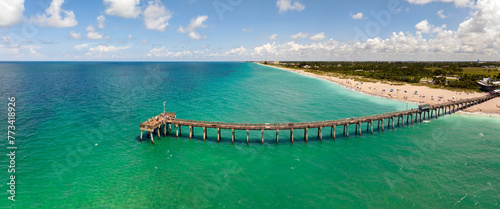 Idyllic summer day over sandy beach at Venice fishing pier in Florida. Summer seascape with surf waves crashing on sea shore