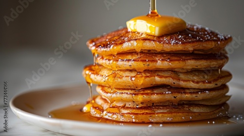 A small stack of golden-brown pancakes topped with a pat of butter and a drizzle of syrup is located at the upper left, against a white background.