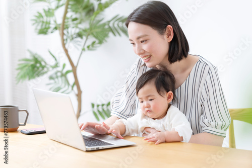 赤ちゃんと一緒にパソコンを使うママ